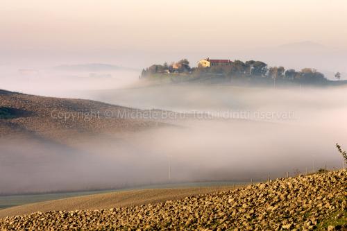 Casolare nelle crete senesi con nebbia